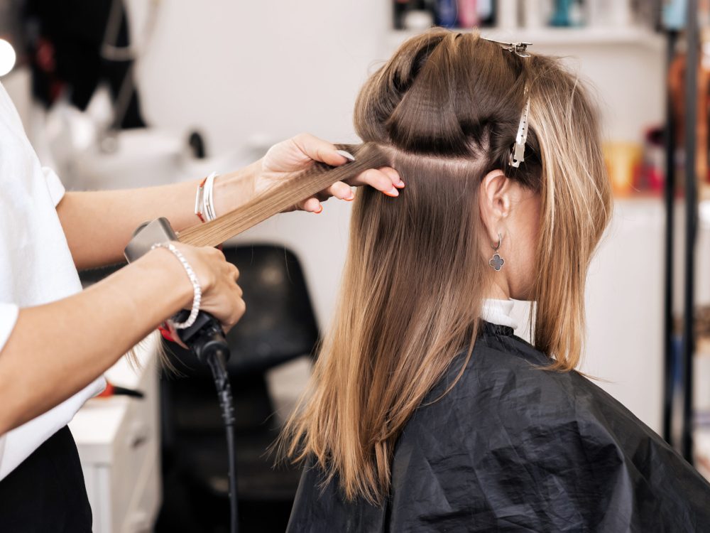 hair stylist creates volume and styling for brown hair on a woman's head in a beauty salon