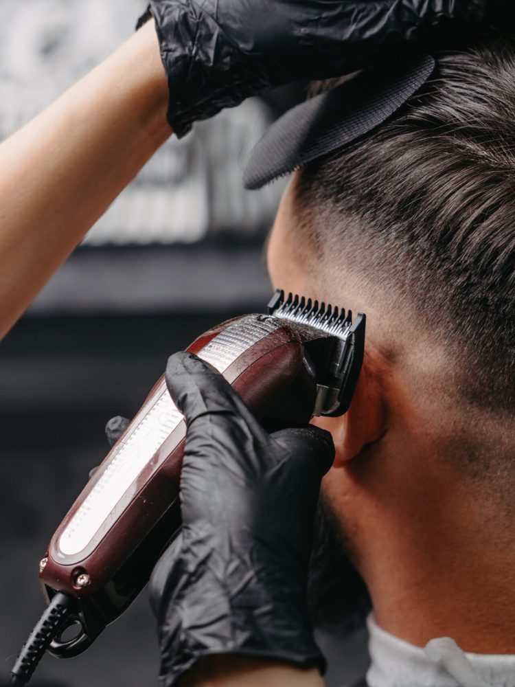 Woman barber cutting hair to a bearded man.